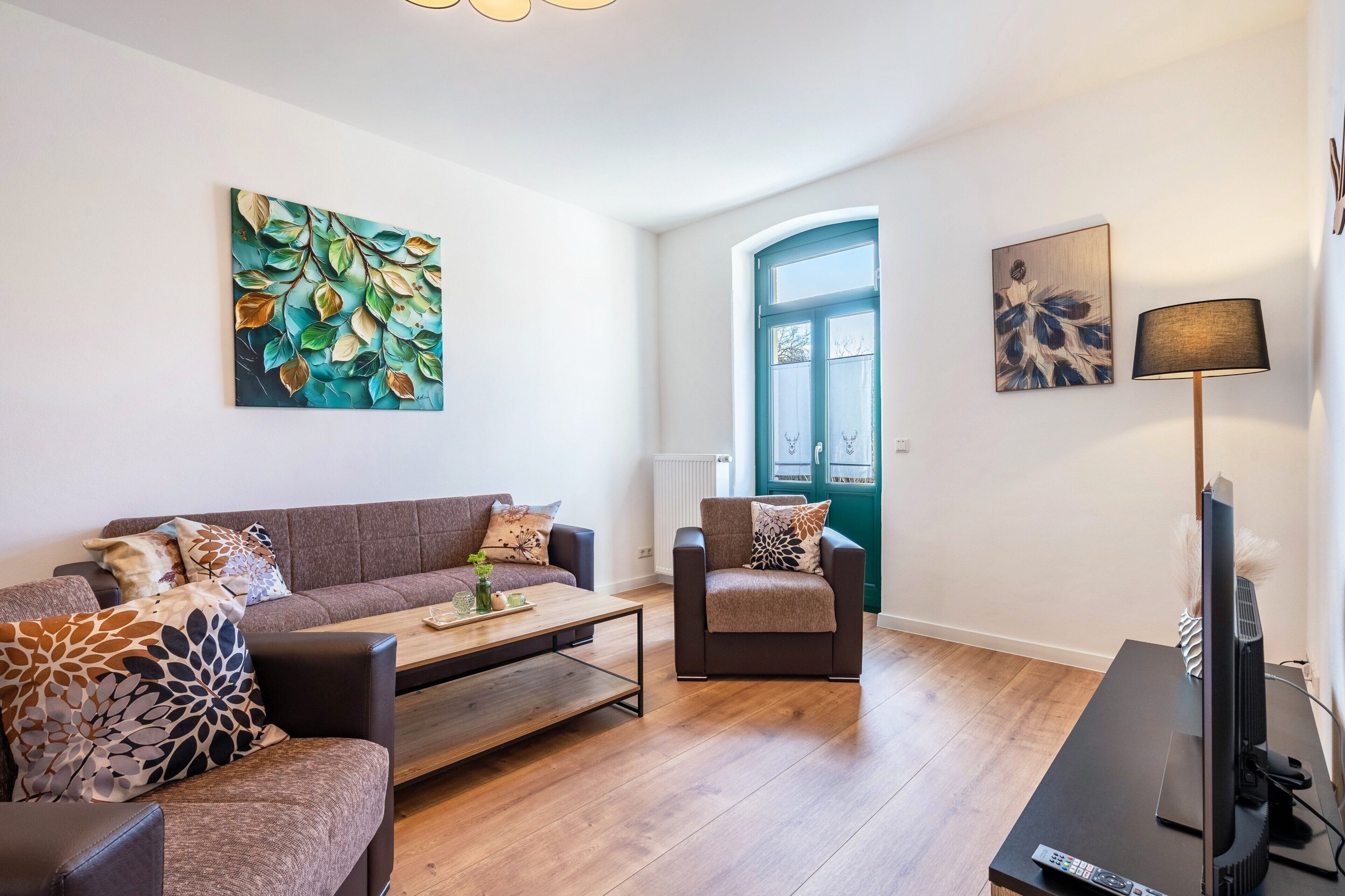 A modern living room with a sofa, armchair, coffee table, and a TV.