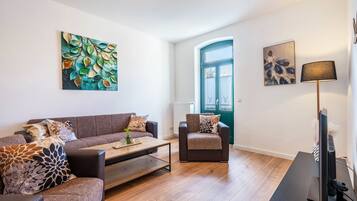 A modern living room with a sofa, armchair, coffee table, and a TV.
