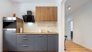 Een moderne keuken met grijze kastjes, een houten aanrechtblad en een ingebouwde oven.