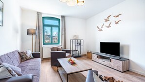 Een moderne woonkamer met een bank, salontafel, tv-meubel en een raam met gordijnen.