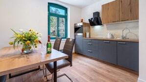 Een moderne keuken met grijze kastjes, een houten aanrechtblad en een groot raam.