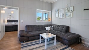 A modern living room with a sectional sofa, a small white table, and a large window.