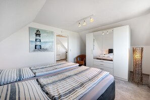 A bedroom with a bed, a chair, a wardrobe, a painting, and a floor lamp.