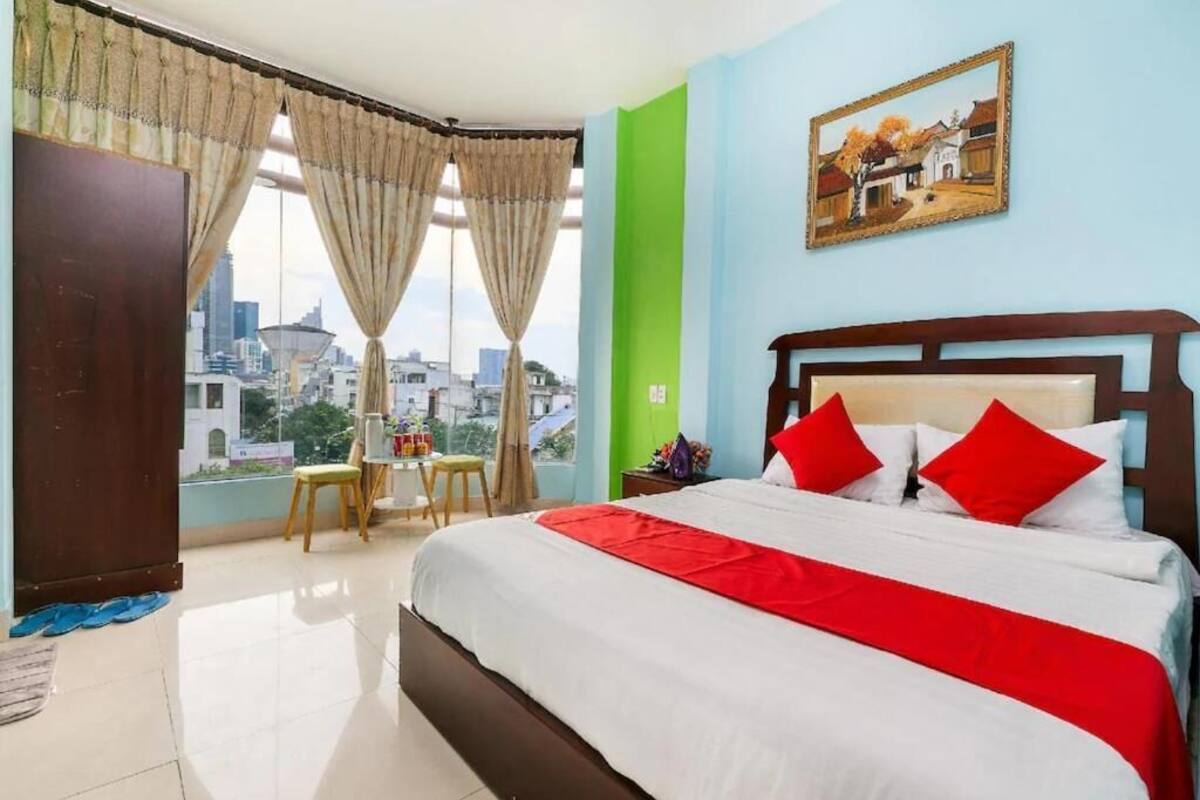 Ein Hotelzimmer mit einem großen Bett, Blick auf die Stadt, einer grünen Akzentwand und einem Bild an der Wand.