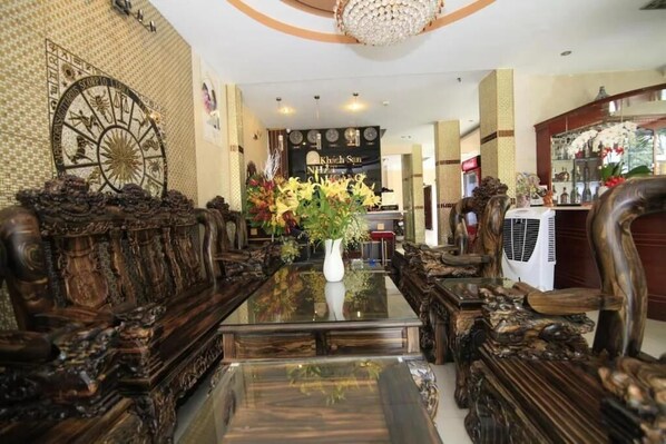 Un comedor lujoso con muebles de madera ornamentada, una mesa de vidrio central y un elemento decorativo en la pared.