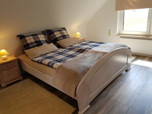 Een slaapkamer met een bed, twee nachtkastjes, een raam en een vloerlamp.