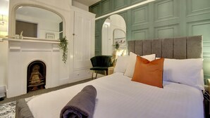 A neatly arranged bedroom with a large bed, a fireplace, and a green accent wall. - Southsea 4BR Getaway with Private Yard (Portsmouth)