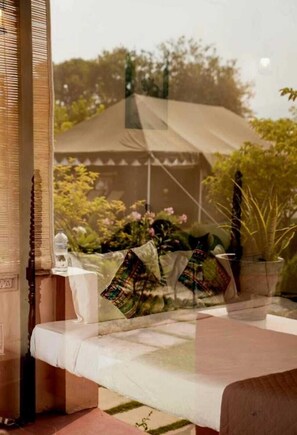 Una habitación con cama, ventana y vista a un jardín.
