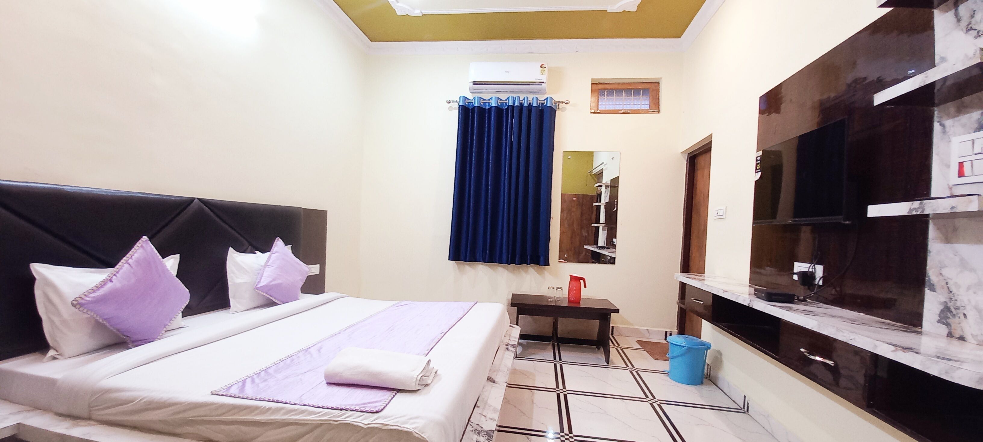 Une chambre d’hôtel avec un lit, une petite table, une télévision et un miroir dans la salle de bain.