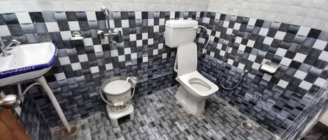 Un bagno con una parete rivestita di piastrelle bianche e nere a scacchi, un lavandino bianco, un water e un bidet.