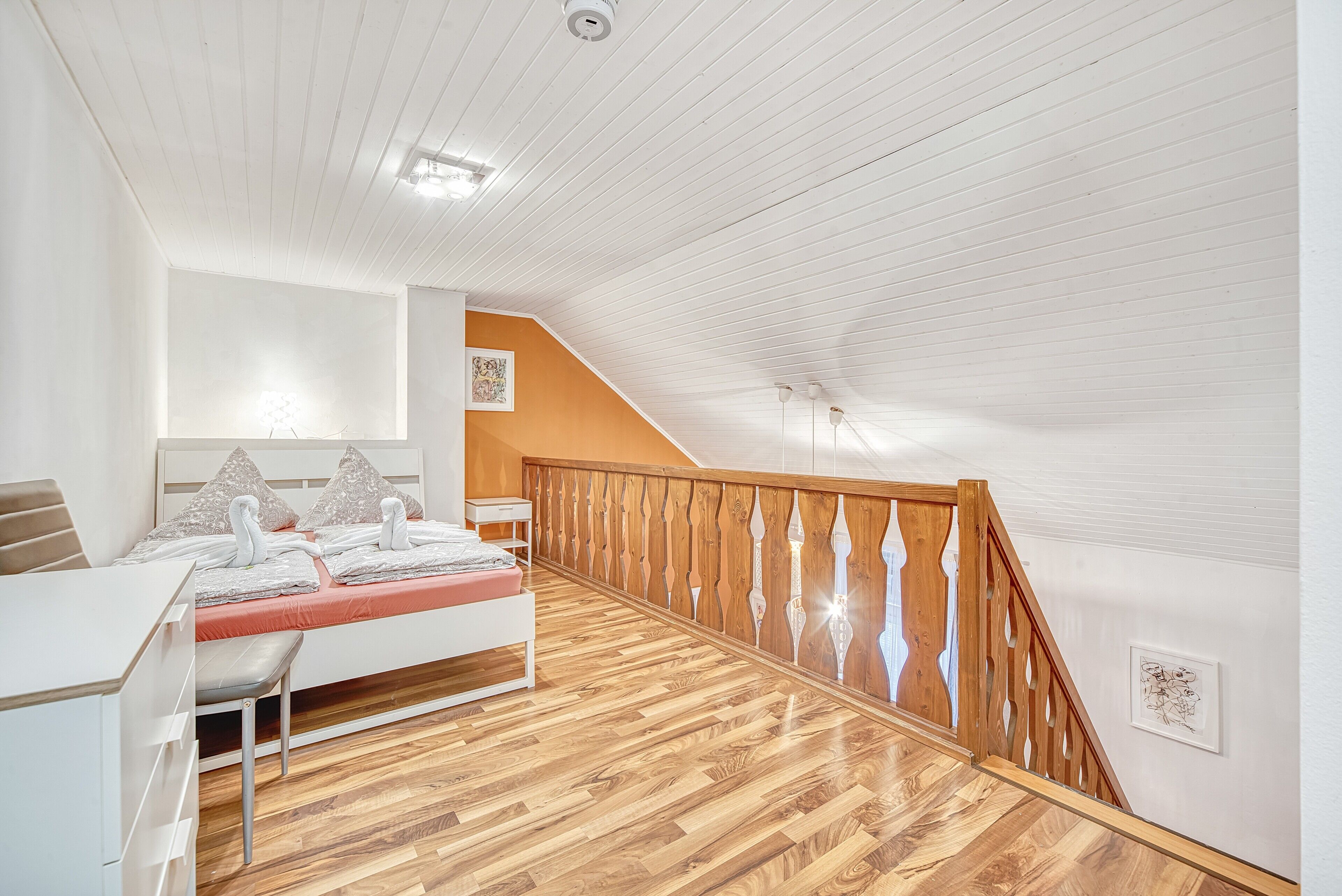 Et soveværelse med seng, skrivebord og trappe.