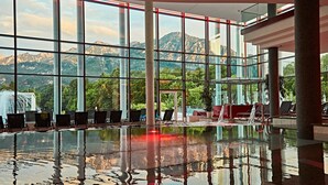 A spacious indoor pool with a mountain view, large windows, and a modern architectural design.