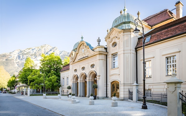 A historic building with ornate architecture, a cobblestone courtyard, and a mountain backdrop.