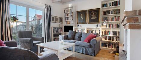 A living room with a sofa, armchairs, a coffee table, and a bookshelf filled with books.