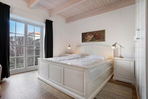 A bedroom with a large window, a bed, a nightstand, and a lamp. - Holiday Home 'Brunnenhaus' with Private Terrace, Garden and Wi-Fi (Walkendorf)