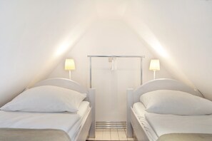 Un petit hôtel d’une seule pièce, comprenant deux lits, une douche et une fenêtre.
