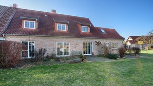 A two-story brick house with a red-tiled roof, large windows, and a well-maintained lawn. - Holiday Apartment 'Jägerkate' with Private Terrace, Shared Garden and Wi-Fi (Walkendorf)