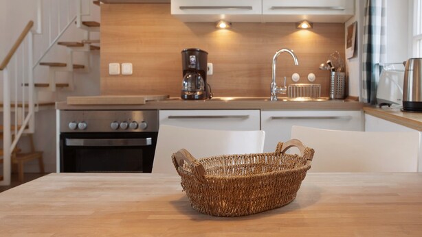 A modern kitchen with a wooden countertop, a stainless steel oven, a coffee maker, and a wicker basket on the table. - Holiday Apartment 'Jägerkate' with Private Terrace, Shared Garden and Wi-Fi (Walkendorf)
