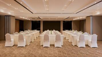 A conference room with multiple tables and chairs, carpeted floor, and recessed lighting.