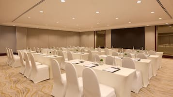 A conference room with rows of tables and chairs, equipped with nameplates and water bottles.