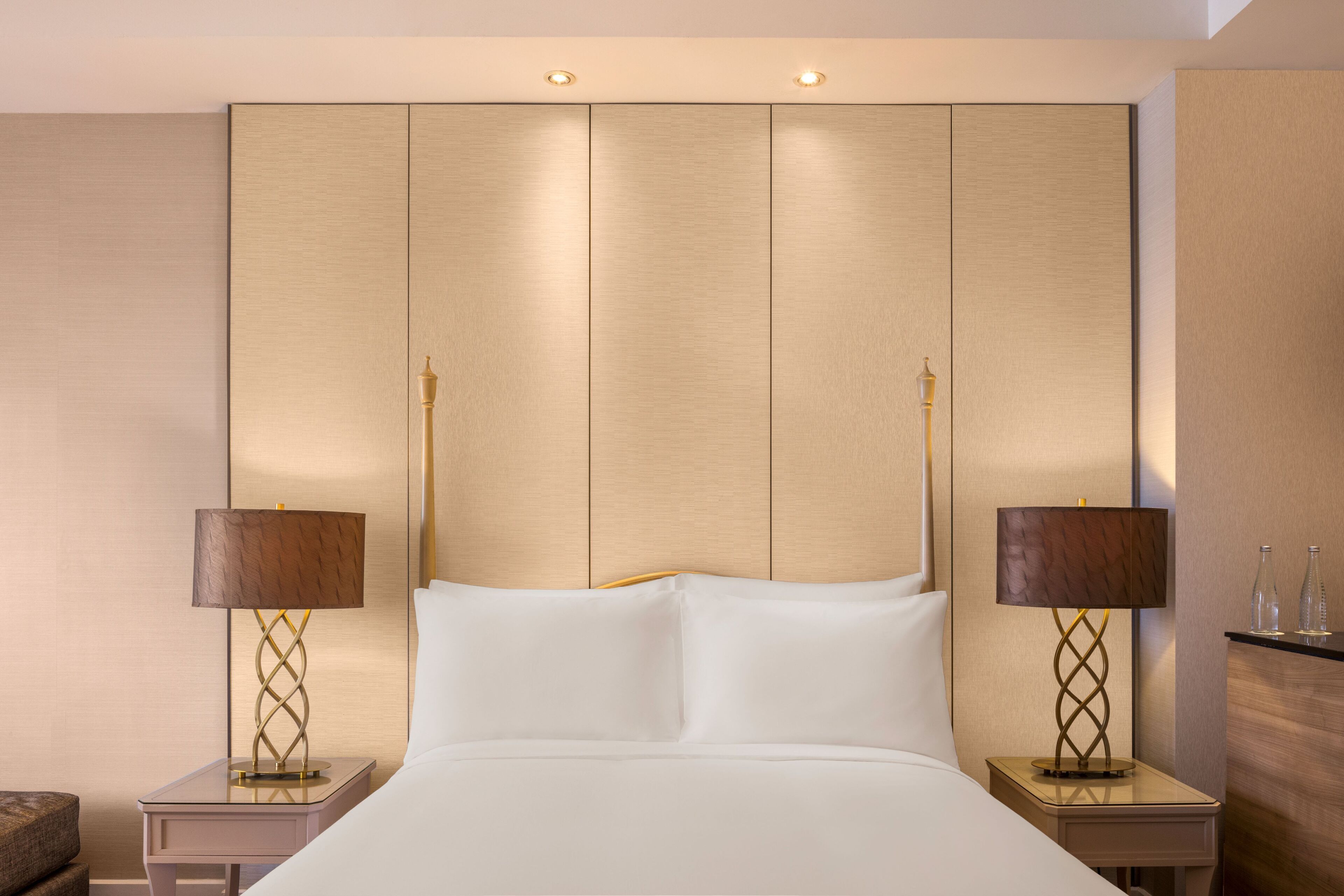 A hotel room with a large bed, two bedside tables with lamps, and a wooden headboard.