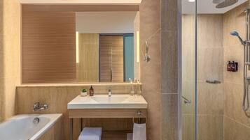 A modern bathroom with a large mirror, a bathtub, a shower, and a vanity with a sink and countertop.