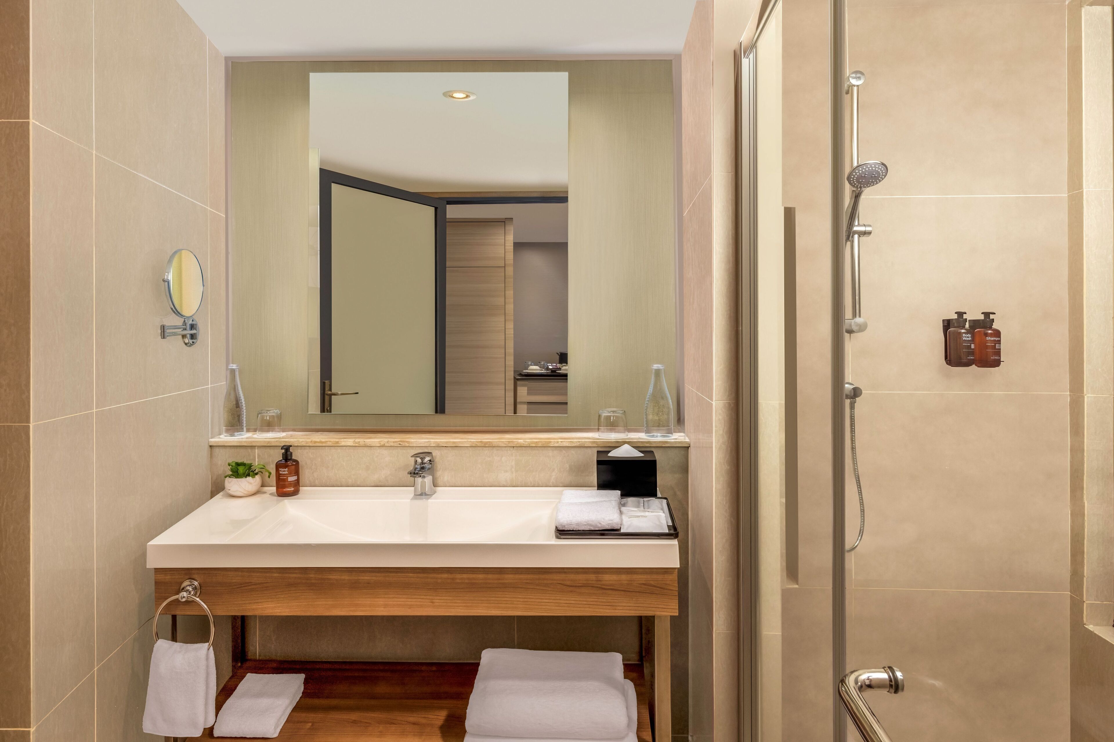 A modern bathroom with a large mirror, a sink, and a shower.