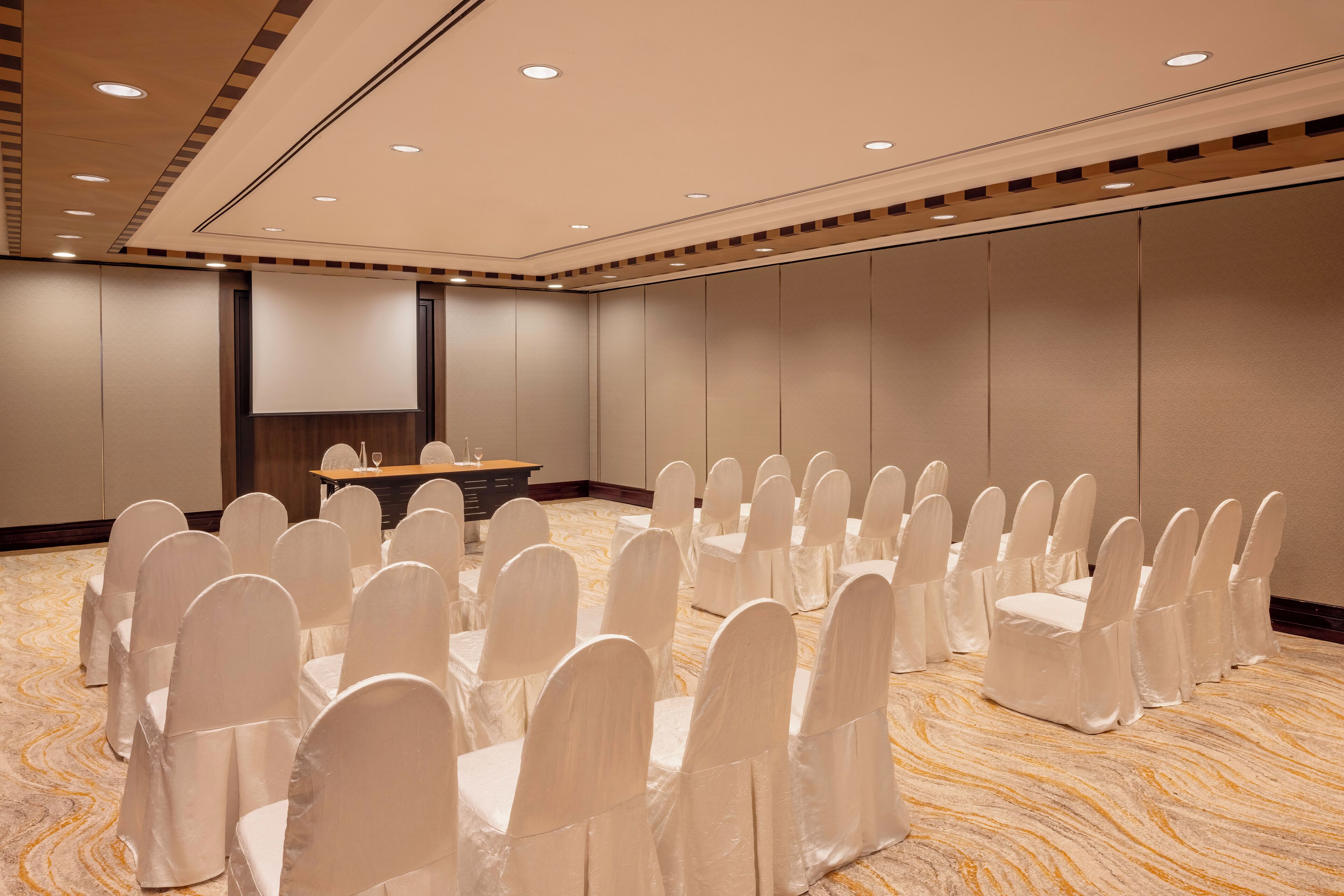 Un salón de conferencias con filas de sillas, un atril y piso alfombrado.