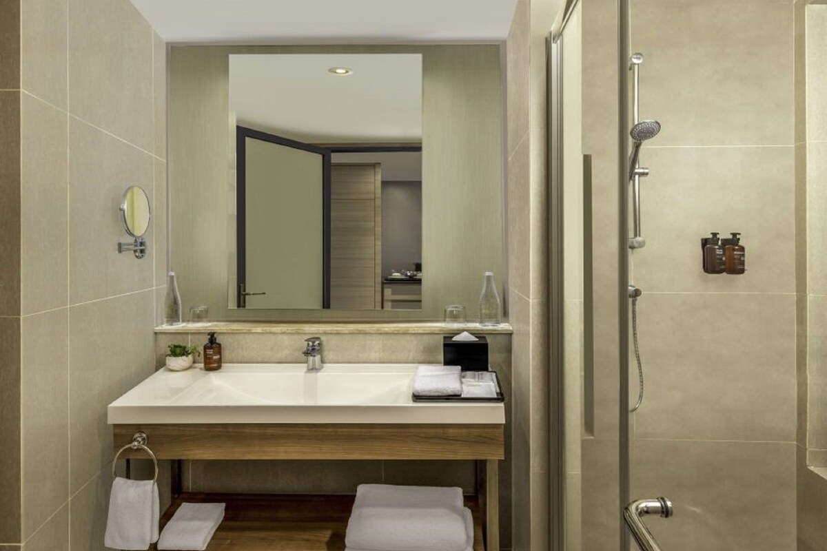 A modern bathroom with a large mirror, a sink, and a shower.