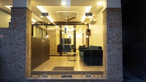 Hall d'hotel con reception, area salotto e ingresso in vetro.