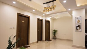 Una hall moderna con tre porte in legno, una pianta in vaso e un lampadario.
