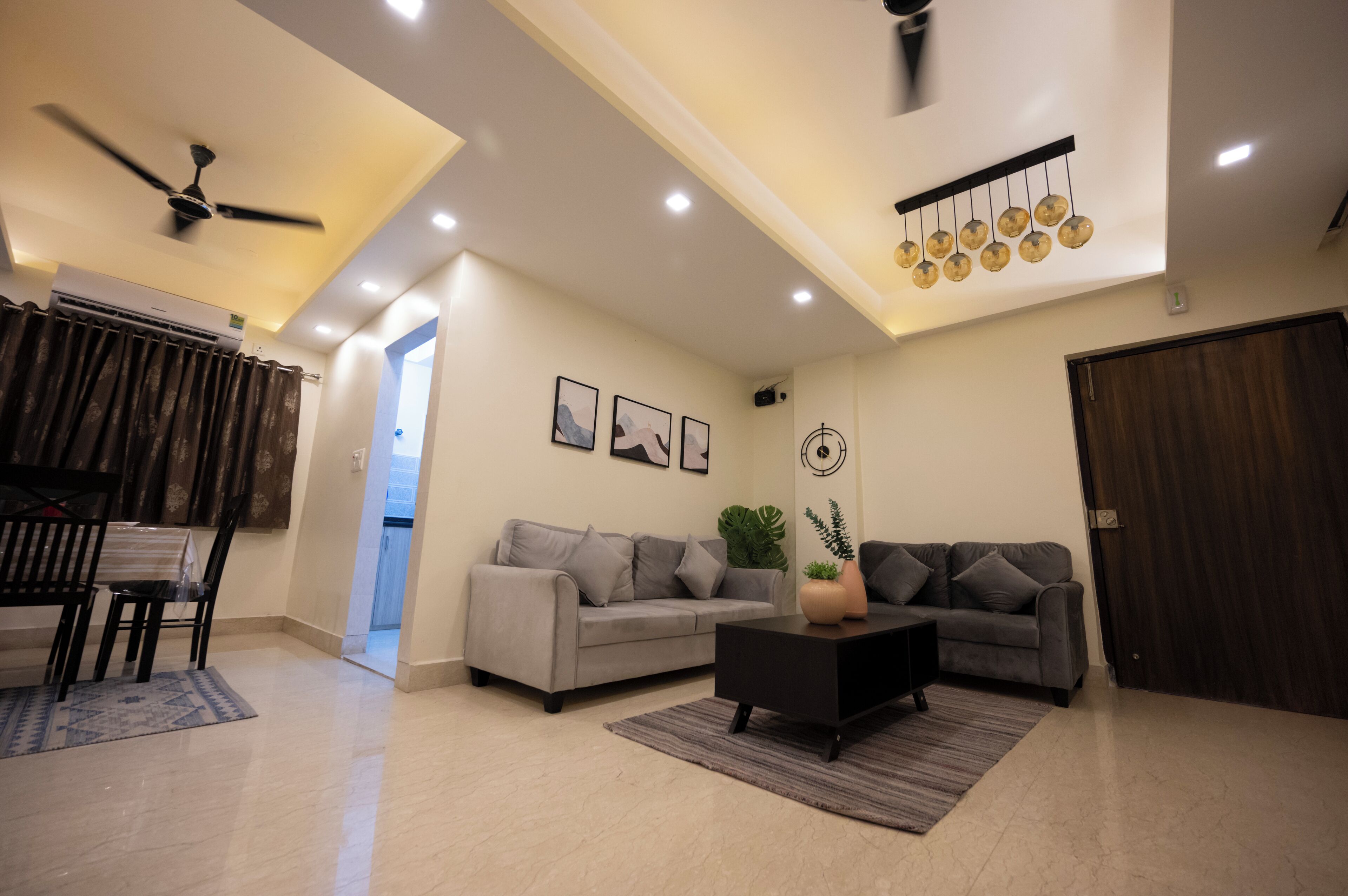 Un salon moderne avec un canapé gris, une table basse noire et un ventilateur de plafond.