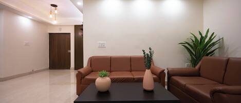 Una sala de estar moderna con un sofá de cuero marrón, una mesa de centro negra y dos jarrones con plantas.