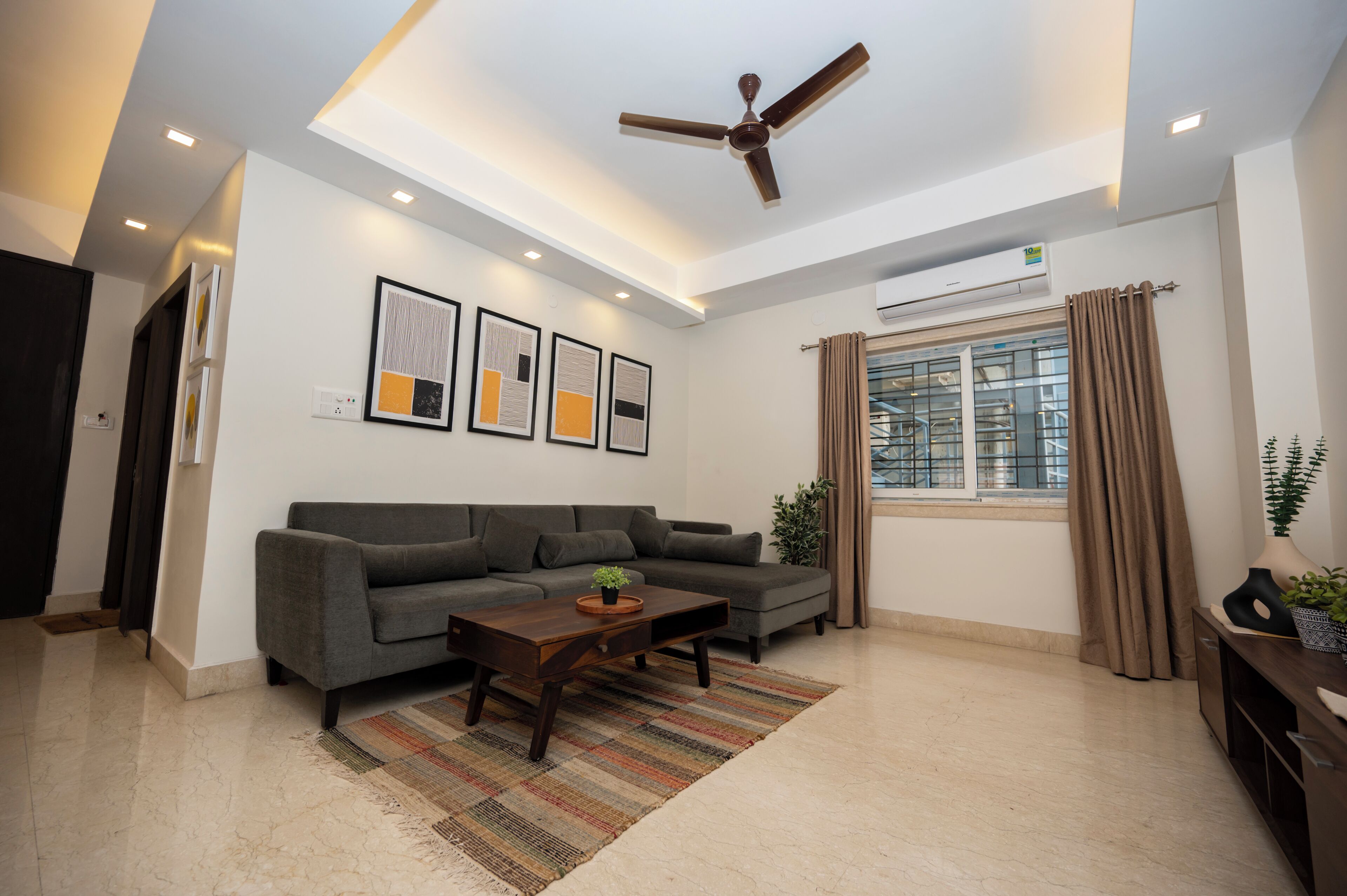 A modern living room with a grey sofa, a wooden coffee table, and a ceiling fan.