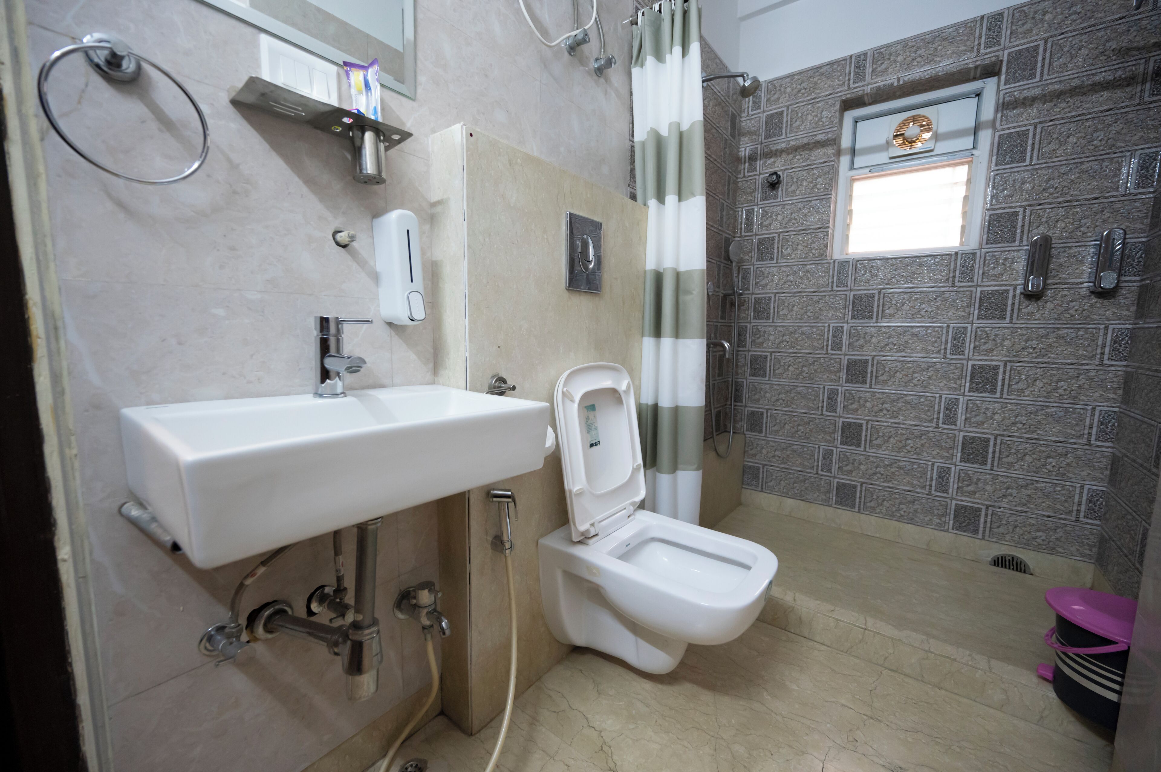 Een badkamer met een wit wastafelmeubel, toilet en douche.