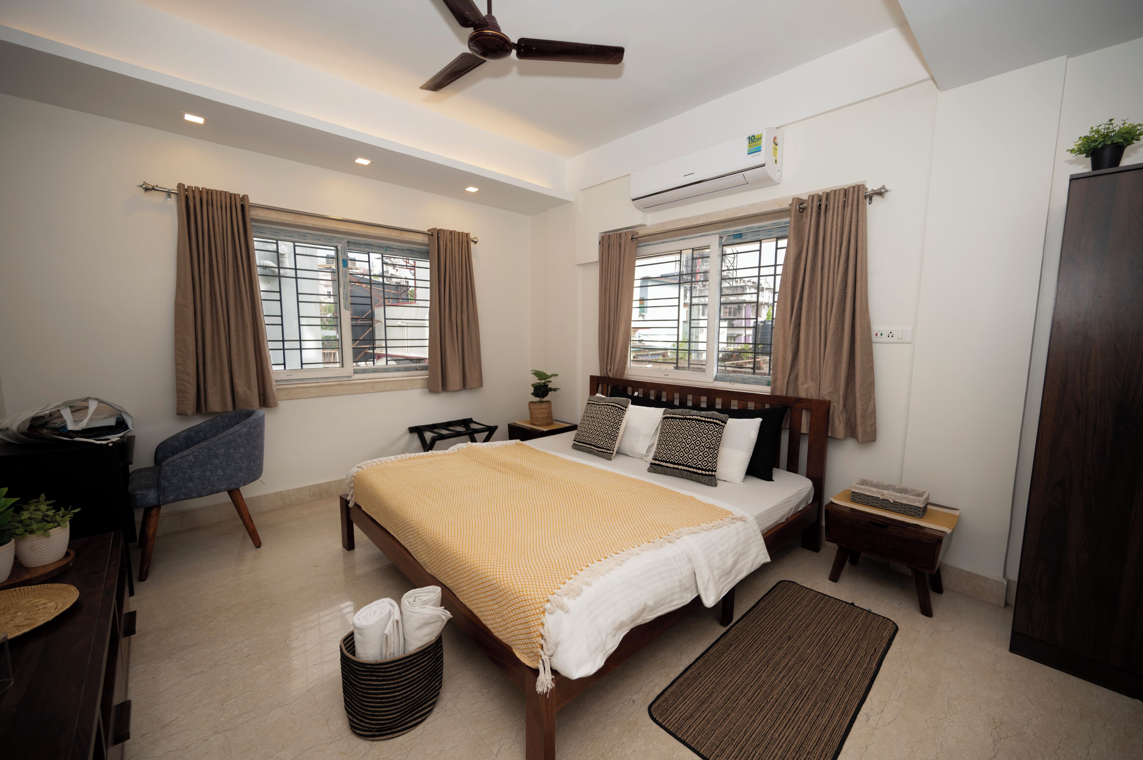 Una habitación de hotel moderna con una cama grande, un escritorio, una silla y un ventilador de techo.