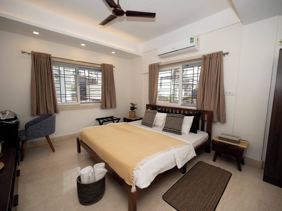 Una habitación de hotel moderna con una cama grande, un escritorio, una silla y un ventilador de techo.