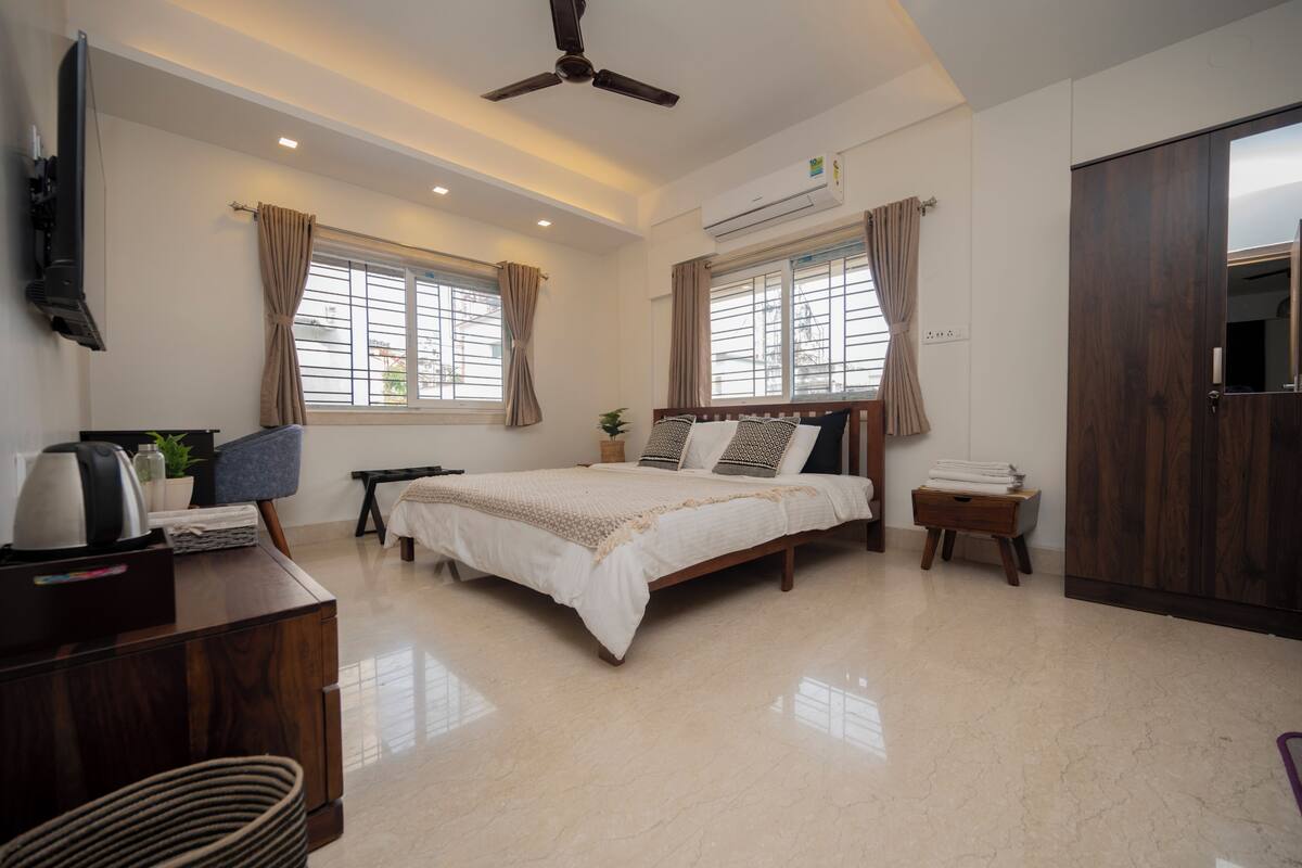 A bedroom with a bed, a desk, a wardrobe, and a ceiling fan.