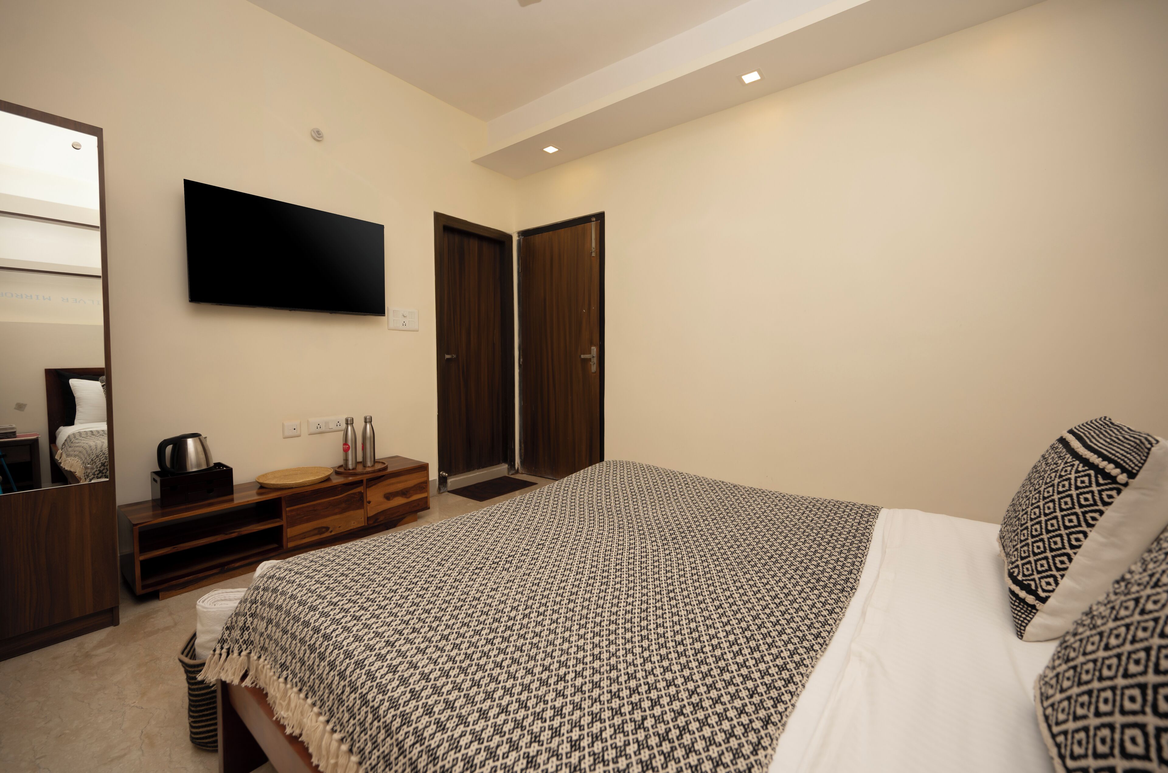 Un dormitorio con una cama grande, un televisor de pantalla plana en la pared, un aparador de madera y un armario.