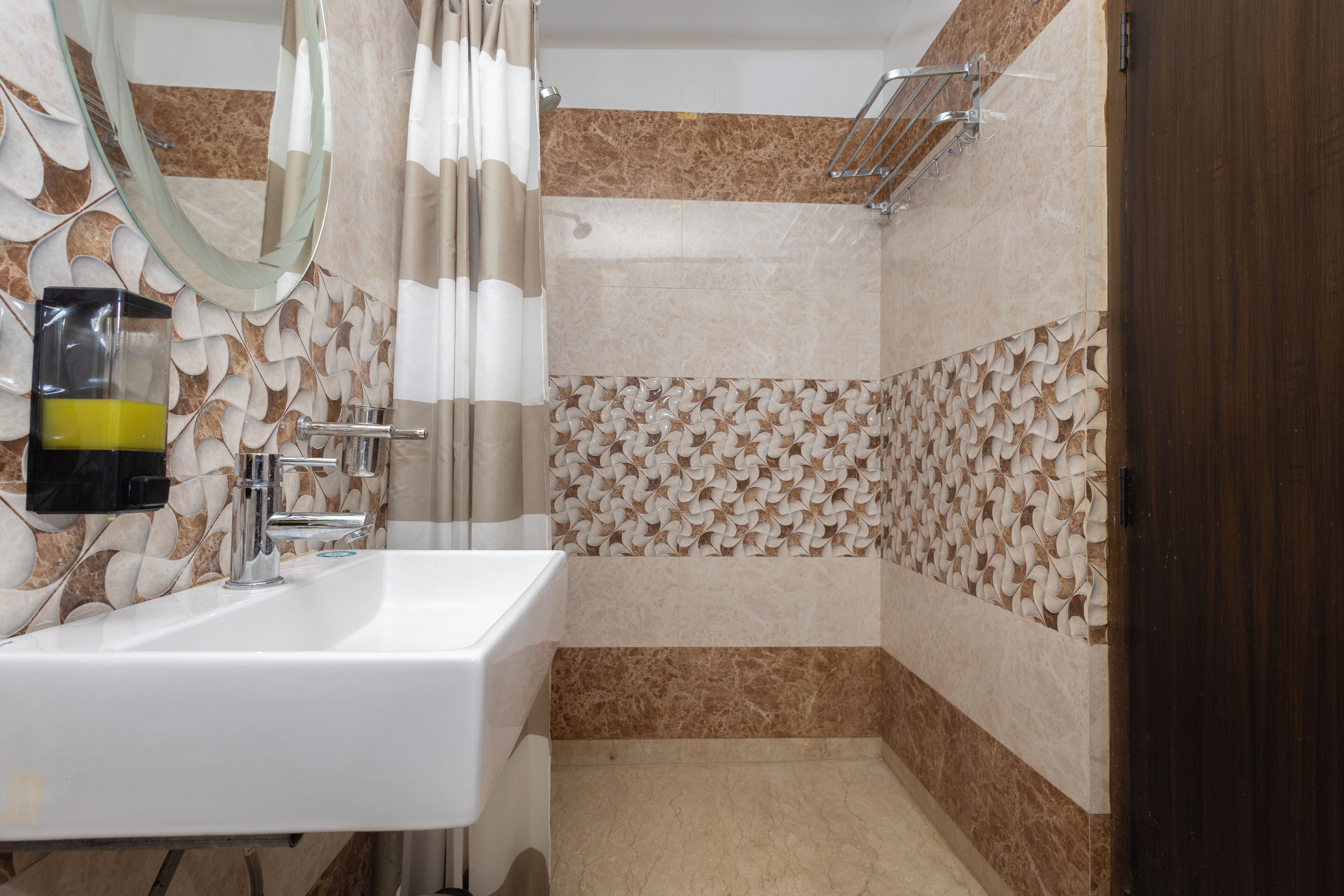 A bathroom with a white sink, a mirror, a shower with a glass door, and patterned tiles.