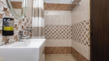 A bathroom with a white sink, a mirror, a shower with a glass door, and patterned tiles.