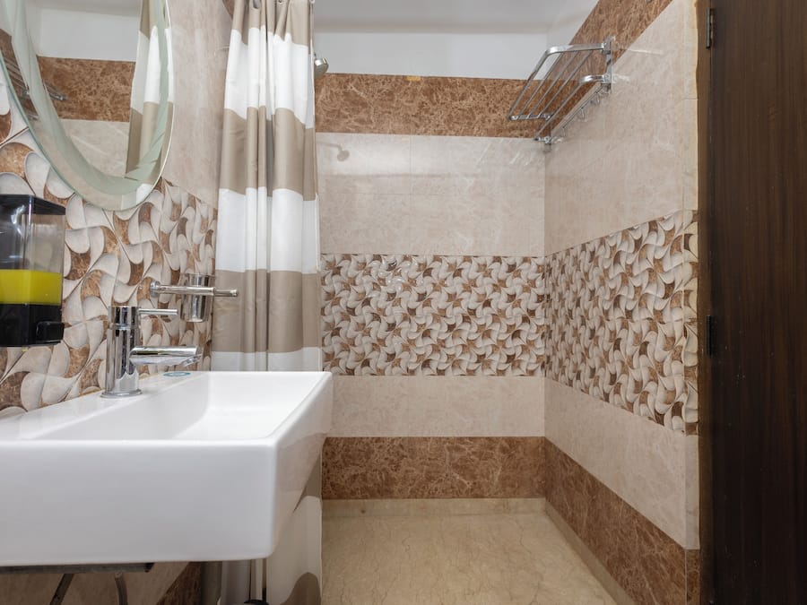 A bathroom with a white sink, a mirror, a shower with a glass door, and patterned tiles.