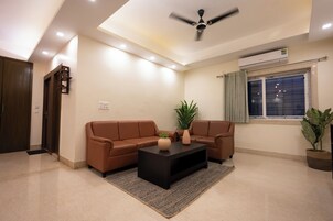 A modern living room with a brown leather sofa, a black coffee table, and a ceiling fan.