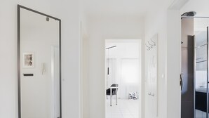 Un pasillo con un espejo grande, una puerta y una pequeña mesa con sillas.