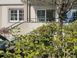 A residential building with a balcony, a tree in front, and a parked car. - Holiday Apartment 'Im Fischerhaus' with Private Terrace and Wi-Fi (Nonnenhorn)