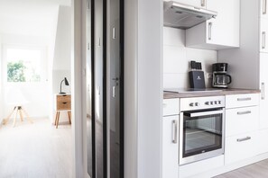 A modern kitchen with white cabinets, a built-in oven, and a coffee maker. - Apartment 'Im Fischerhäusle' with Balcony and Wi-Fi (Nonnenhorn)