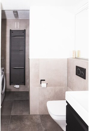 Une salle de bain moderne équipée de toilettes, d’un porte-serviettes et d’un lave-linge.