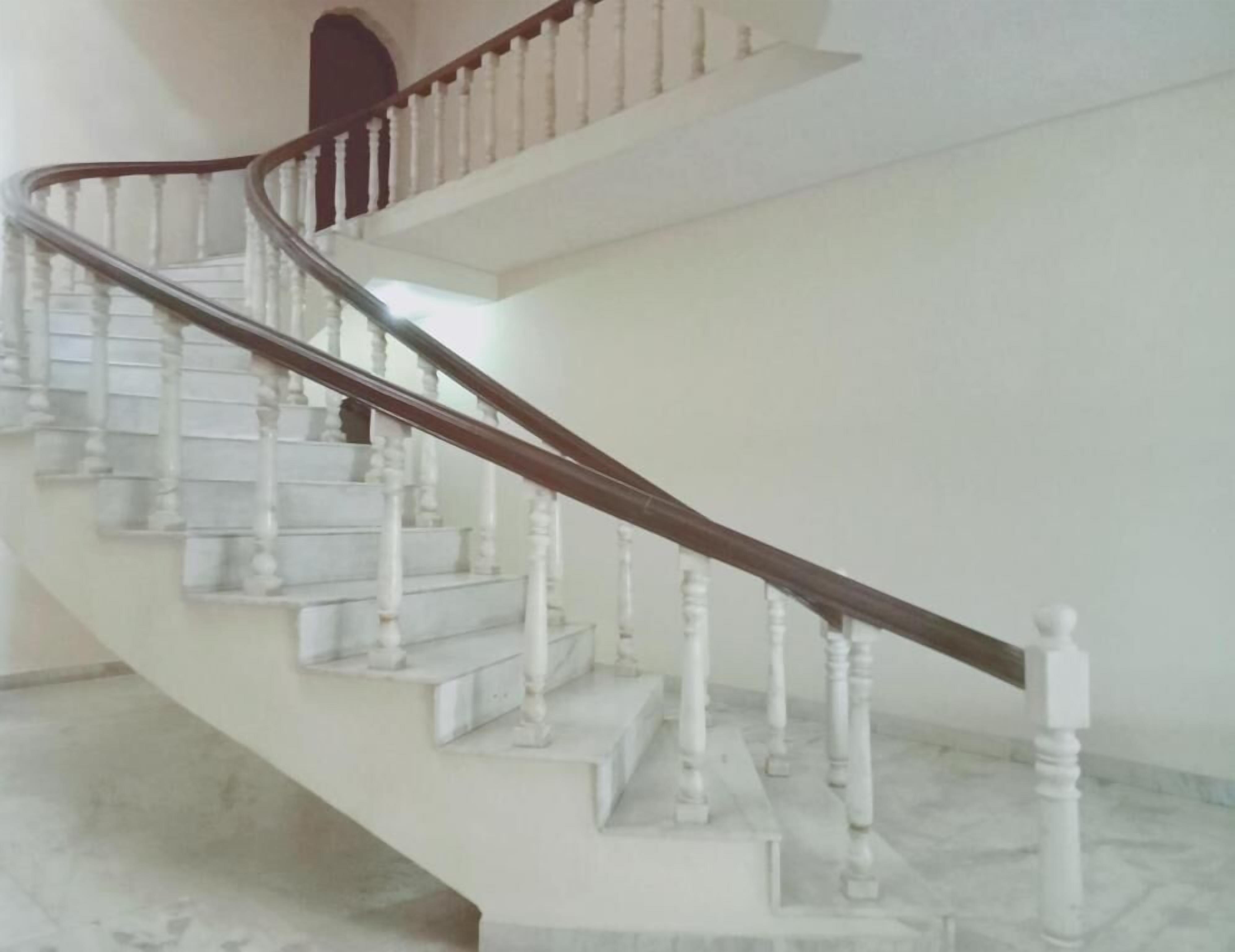Una escalera con balaustres blancos y barandilla de madera que conduce a un piso superior.