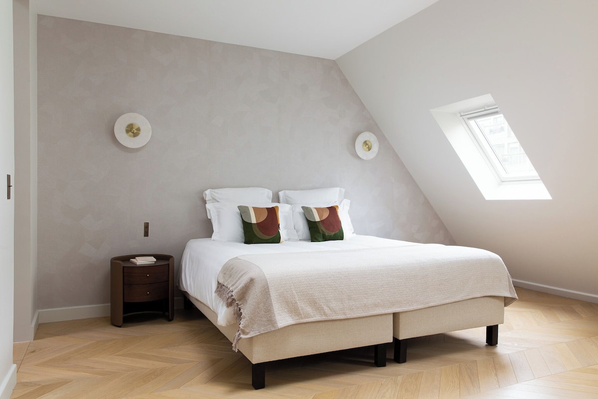 Una camera da letto con un letto, comodini e un lucernario.
