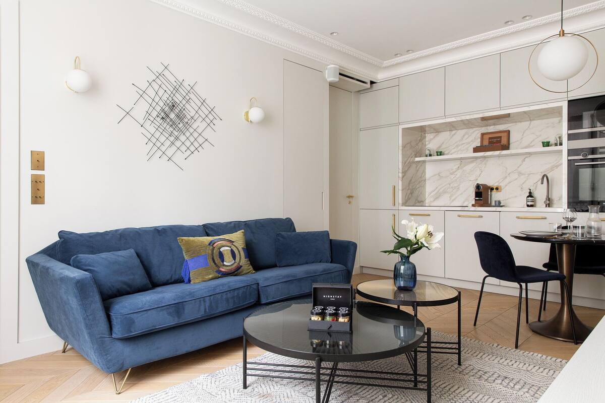 Un soggiorno moderno con un divano blu, un tavolino da caffè e una zona pranzo con tavolo e sedie.